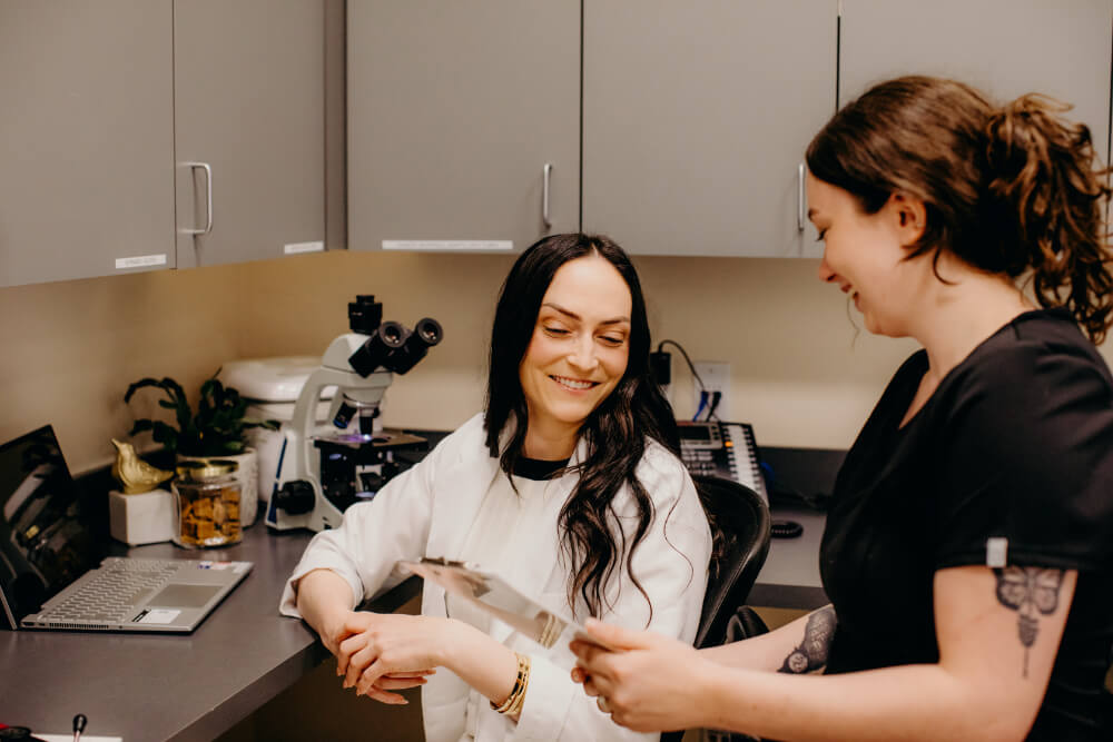 Veterinarian and technician reviewing lab results by a microscope, representing infectious disease diagnosis in Lacey